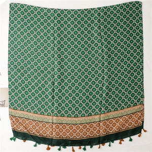Detail of green ethnic scarf featuring geometric patterns and woven tassel fringe finish