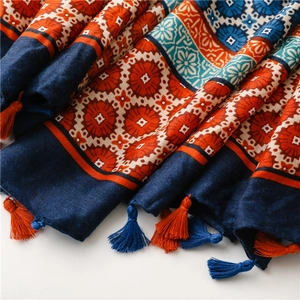 Detail of bohemian printed scarf showing fabric texture and vibrant orange-blue tassels