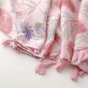 Close-up of pink floral scarf fabric with purple daisies and tassel fringe detail