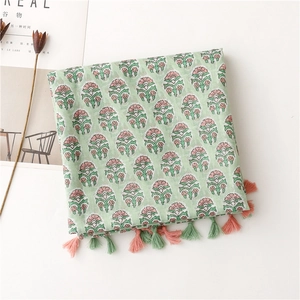 Detail of light green floral scarf with cotton linen texture and fringe tassels