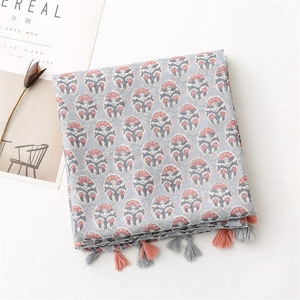 Close-up of blue floral cotton linen scarf with orange and grey tassel fringe detail