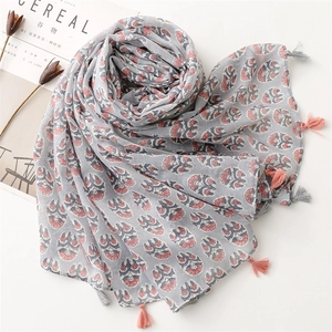 Detailed view of light blue cotton linen scarf with floral print and fringe tassels