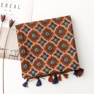 Detail of floral patterns and fringe on a caramel cotton linen scarf with a magazine