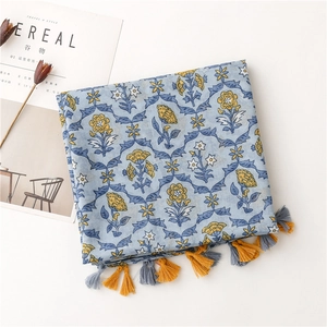 Detail of light blue floral cotton linen scarf with soft yellow tassels and botanical print