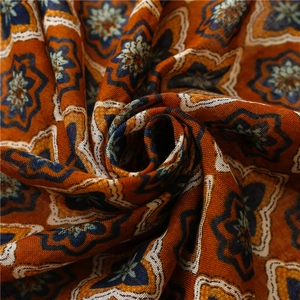 Detailed close-up of orange linen scarf featuring blue star floral bohemian patterns
