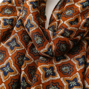 Close-up of orange cotton linen scarf showing geometric floral pattern and fabric texture