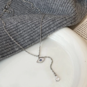 Detailed shot of silver evil eye pendant with blue crystal and water drop gemstone charm