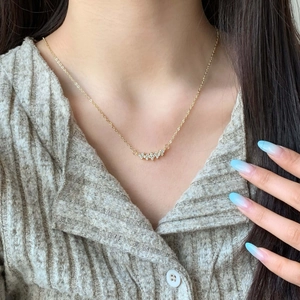 Elegant 18K gold plated necklace with curved cubic zirconia cluster on a female model