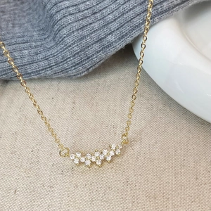 Detailed close-up of a gold floral cluster pendant with zircon crystals on a fine chain