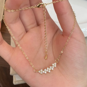 Exquisite gold flower pendant necklace with white zircons held in hand for scale