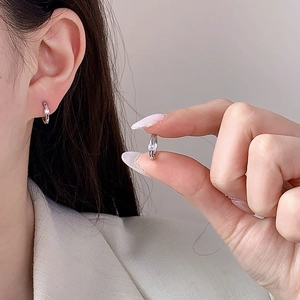 Minimalist silver huggie earrings with rectangle zircon stone shown for size perspective