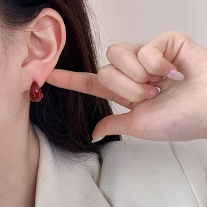 Elegant deep red teardrop earrings in gold-plated U-shape design worn by a model