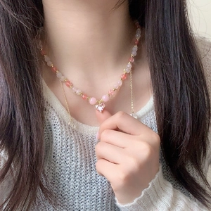 Pink beaded necklace with heart-shaped crystal pendant and gold accents on a model