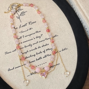 Macro view of pink quartz beaded heart necklace with gold accents on poetic background
