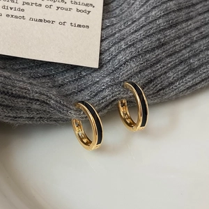 Chic gold-plated hoop earrings with black enamel inlay on a grey knit texture