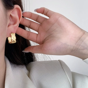 Elegant gold square quilted earrings with matelassé design shown on model's ear