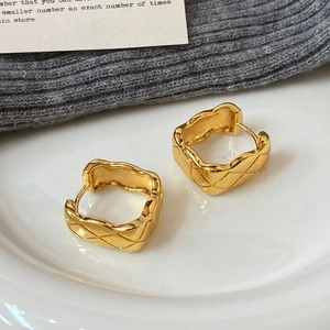 Elegant gold square earrings with diamond quilted pattern on white ceramic tray