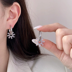 Boucles d'oreilles fleur géométrique en argent avec zircons, portées sur l'oreille