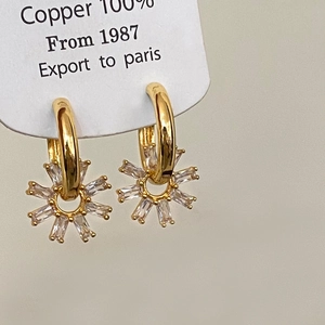 Gros plan de boucles d'oreilles huggie en cuivre doré avec breloques en zircon