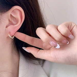 Créoles élégantes torsadées en or rose avec un design géométrique minimaliste portées à l'oreille