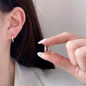 Élégantes boucles d'oreilles créoles en or rose avec zircons, vue sur le mannequin