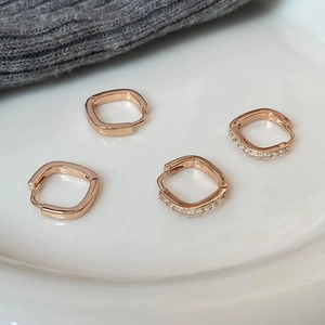 Détail de créoles carrées en or rose avec des textures minimalistes et serties de pavé