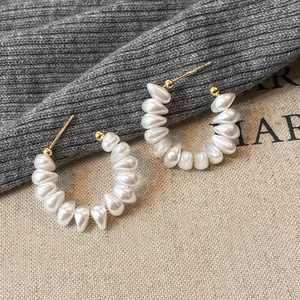 Elegant C-shaped pearl hoop earrings with gold-tone accents on a minimalist background