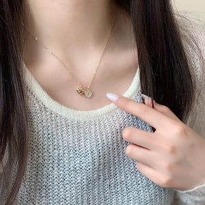 Detail of a minimalist gold necklace with double heart pendant on a model's neck