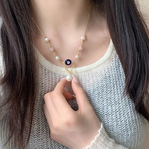 Collier doré multicouche avec perles, pierres roses et pendentif œil bleu sur modèle