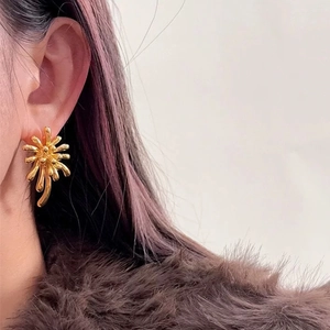 Boucles d'oreilles clous géométriques dorées feu d'artifice portées par un mannequin