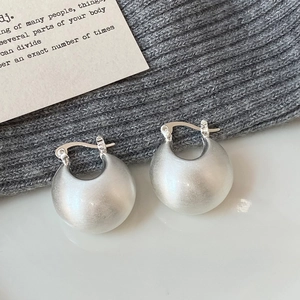 Macro shot of silver C-shaped chunky earrings with matte brushed finish and secure clasp