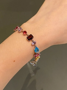 Detailed view of a multi-color gemstone bracelet with various shapes on a female wrist