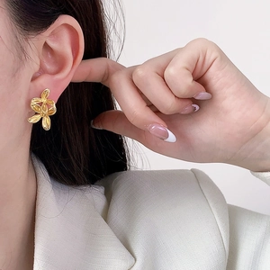 Elegant gold flower stud earrings with irregular natural petals shown on a model
