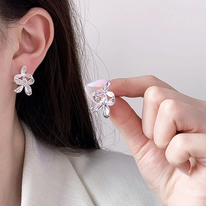Elegant silver flower earrings with zircon center inlay worn on ear for minimalist style