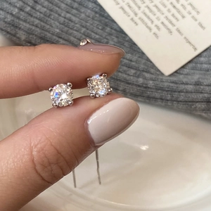 Macro view of geometric round zircon stud earrings with classic four-prong silver setting