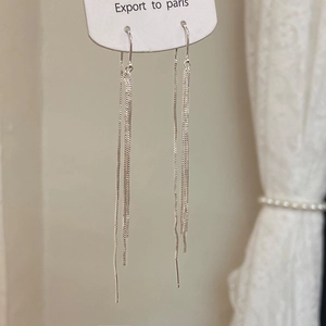 Detail of silver long tassel drop earrings with multiple fine metal chains on card