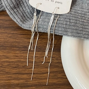 Detail of silver long tassel earrings with delicate metal chains on elegant background