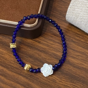 Bracelet en perles de cristal bleu avec breloque rose blanche sur fond en bois
