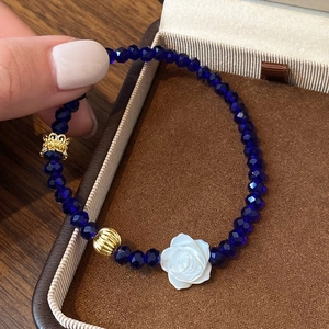 Bracelet de perles en cristal bleu avec breloque rose blanche et détails dorés
