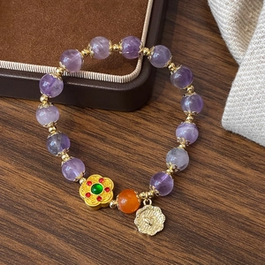 Bracelet élégant en améthyste avec breloque fleur dorée sur une table en bois rustique