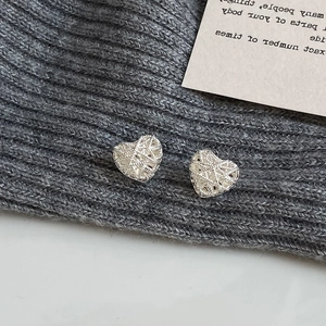 Detailed macro view of heart-shaped hollow woven mesh earrings in silver metal finish