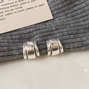 Makroaufnahme silberner Metallohrringe mit Hammerschlag-Textur im minimalistischen Design