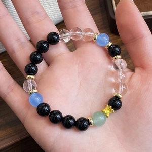 Hand holding beaded bracelet with black agate, green aventurine, and golden butterfly charm