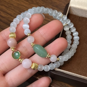 Bracelet double rang en perles œil de chat et quartz rose tenu dans la main
