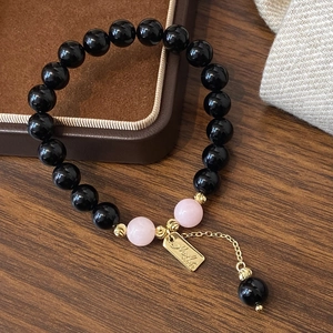 Bracelet élégant en quartz fraise et jade avec breloque dorée sur plateau en velours