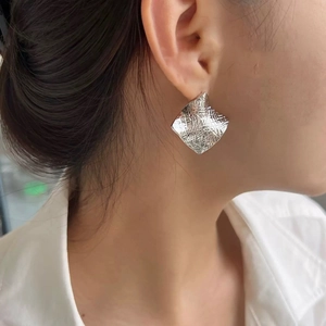 Detail shot of silver square earrings with hammered texture worn by a female model