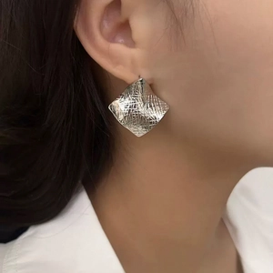 Minimalist silver square earrings with wrinkled texture shown on a female model