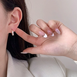 Minimalist gold plated hoop earrings with three zircon stones worn by a model