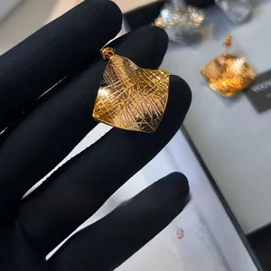 Macro detail of irregular geometric gold earrings with textured brushed metal finish