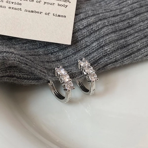 Detailed close-up of polished silver hoop earrings with three vertical inset zircons